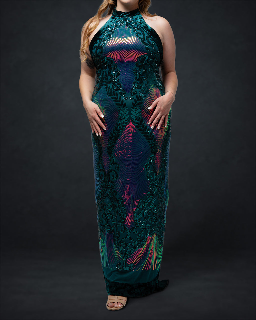Woman wearing a long, dark green dress with colorful patterns on a black background [model_size:XL] [dress_size:XL] [color_id:green-purple] [editorial]