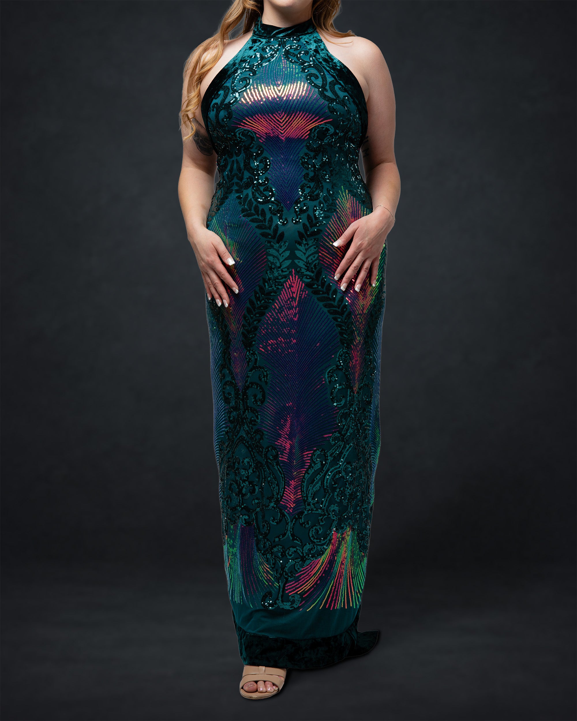 Woman wearing a long, dark green dress with colorful patterns on a black background [model_size:XL] [dress_size:XL] [color_id:green-purple] [editorial]