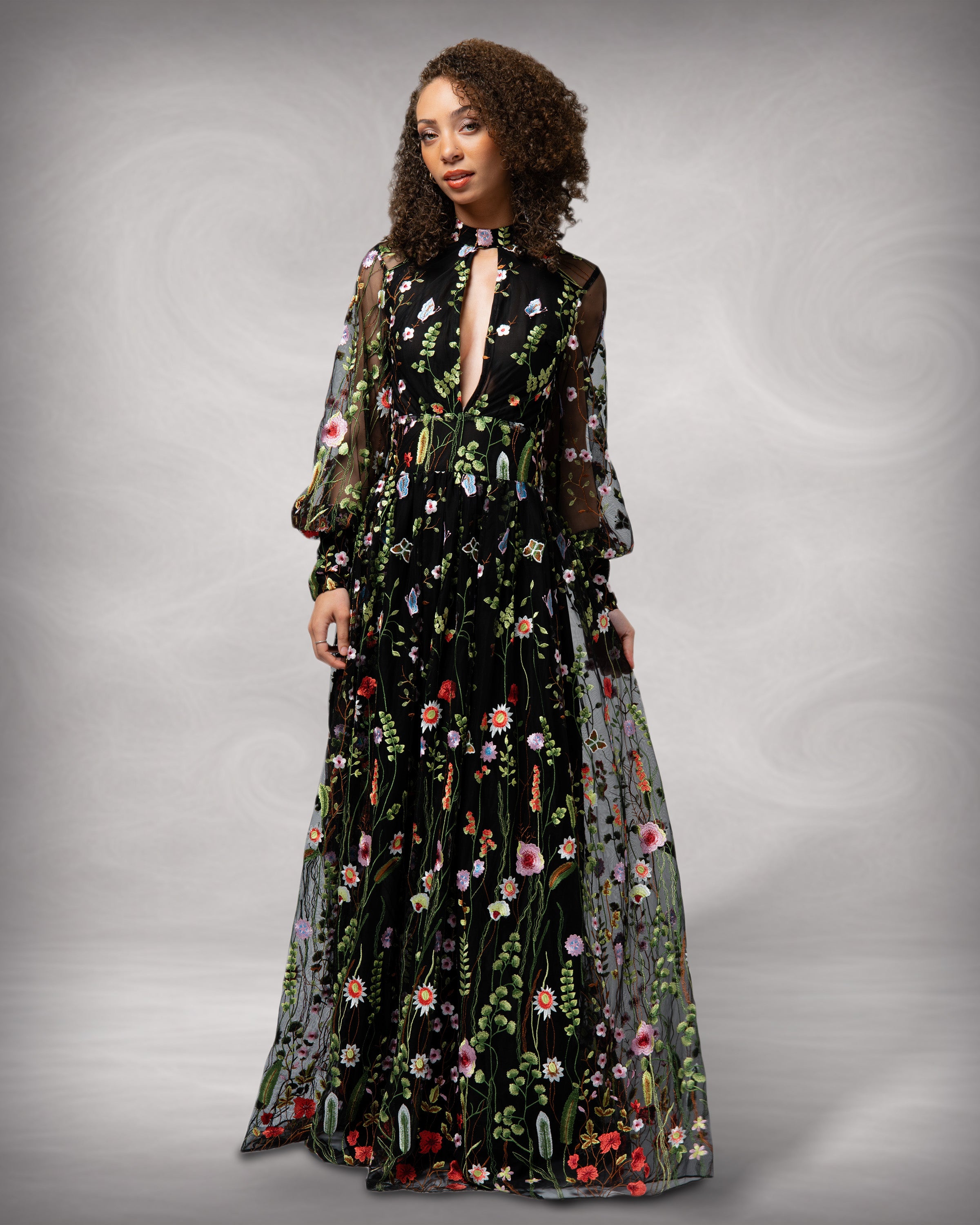 Woman wearing a black floral dress against a gray background [color_id:black] [hero]