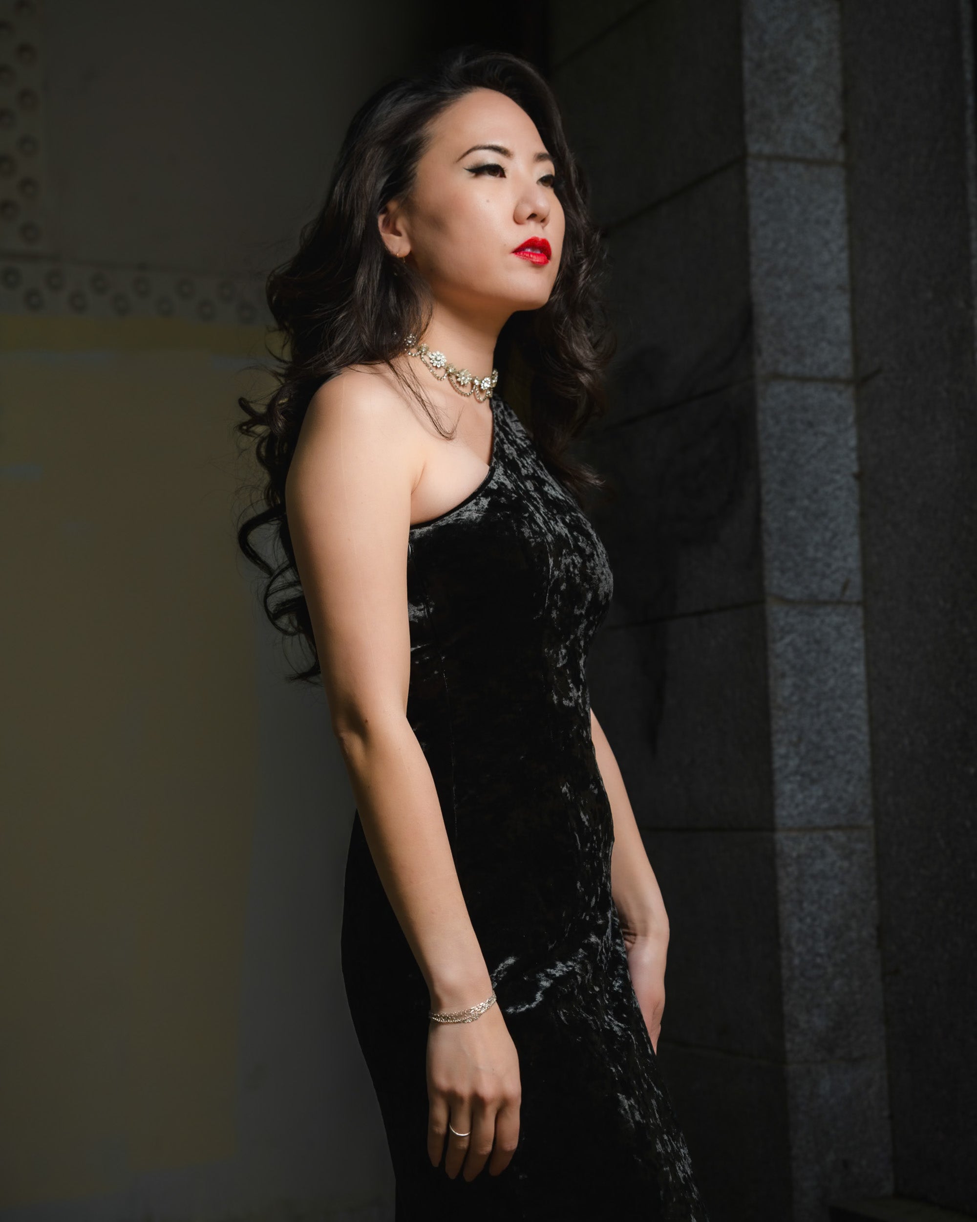Woman in a black dress standing against a dark background [color_id:gunmetal] [editorial] [model_size:XS] 