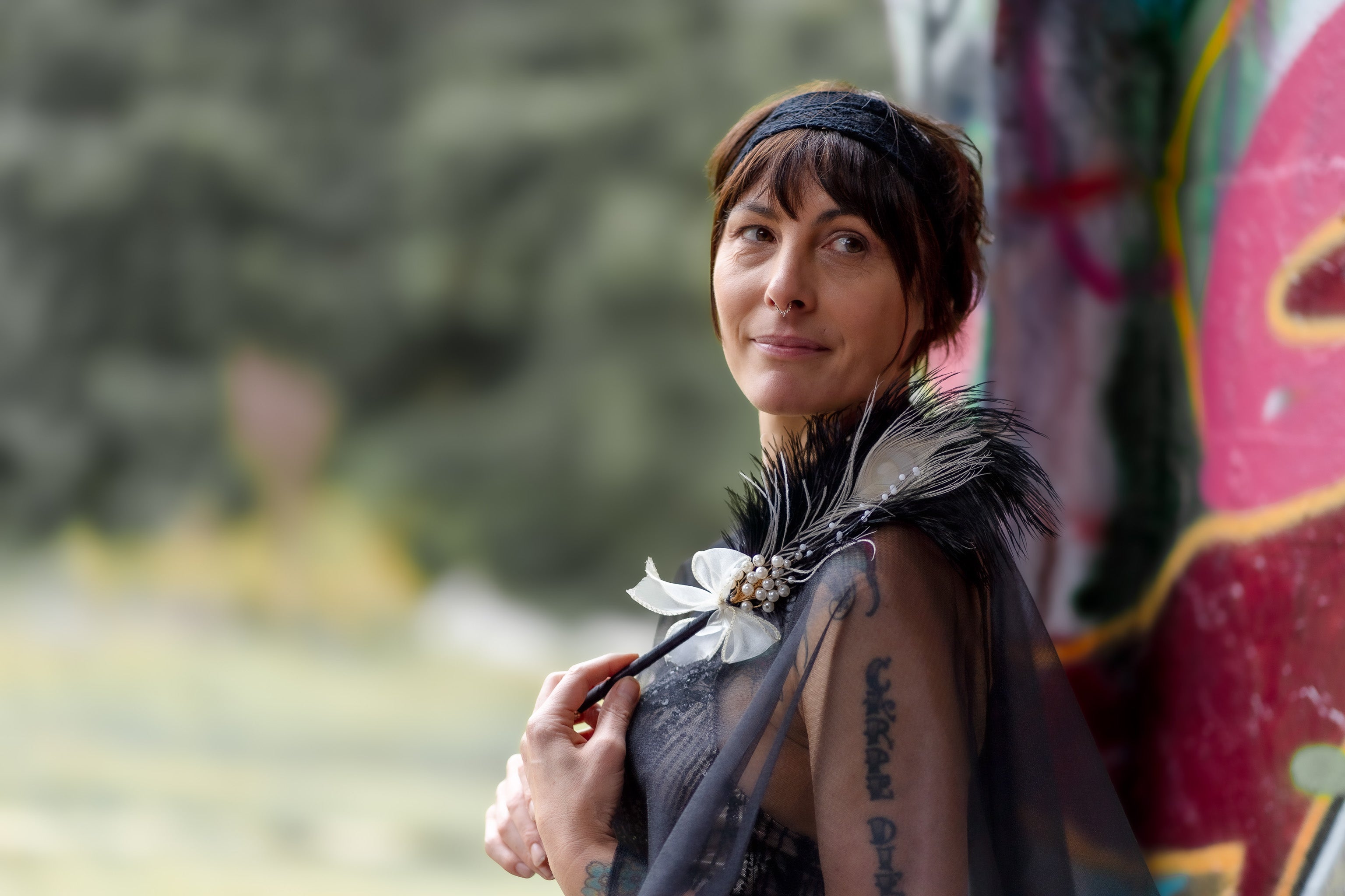 Portrait of Anna Flowers in an elegant formal black dress holding a feather