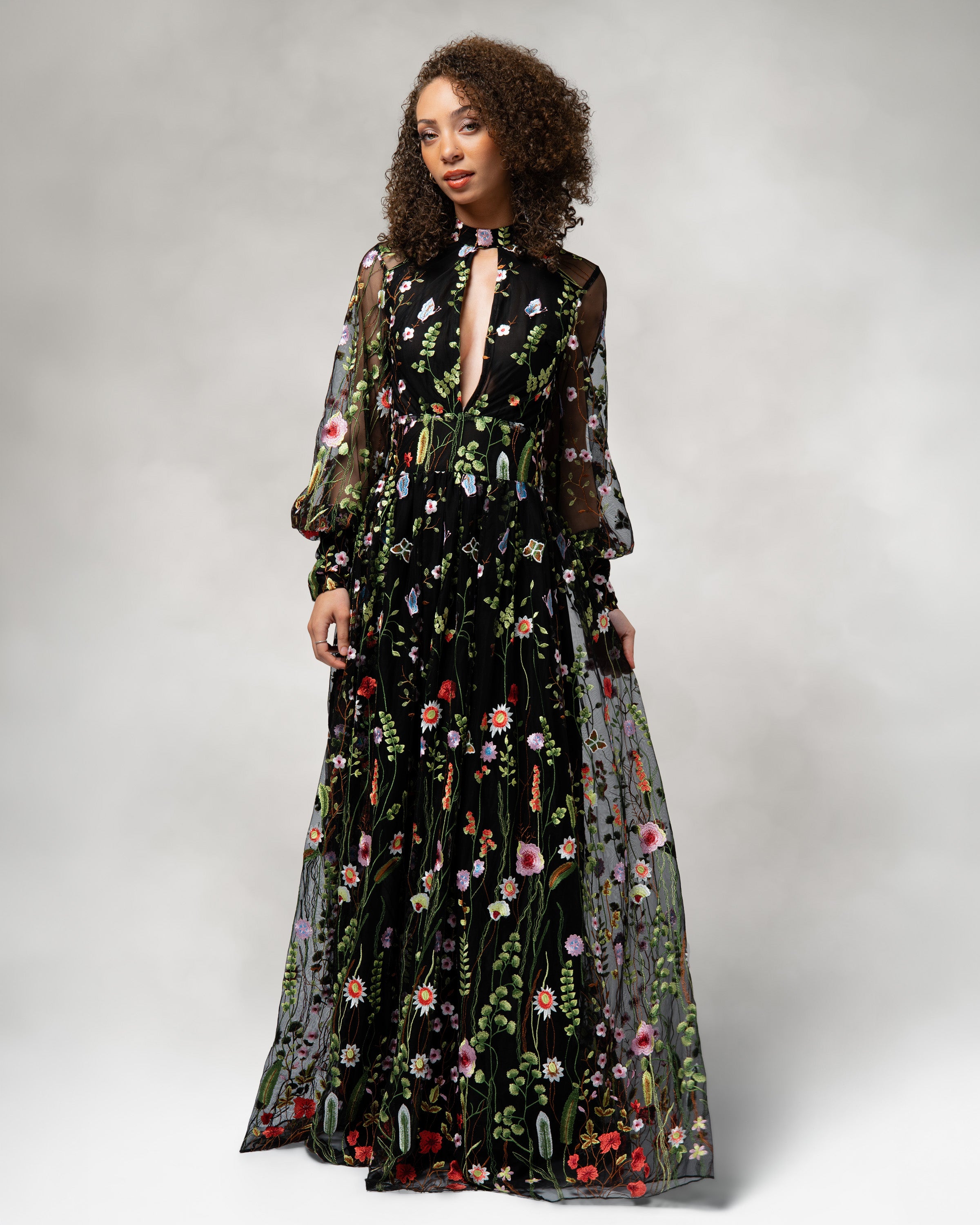 Woman wearing a black floral dress against a plain background [color_id:black]