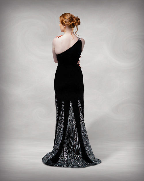 Woman wearing a black evening gown with a subtle pattern on a gray background