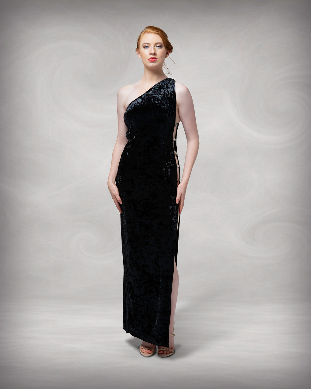 Woman wearing a black one-shoulder evening gown against a neutral background [color_id:black]