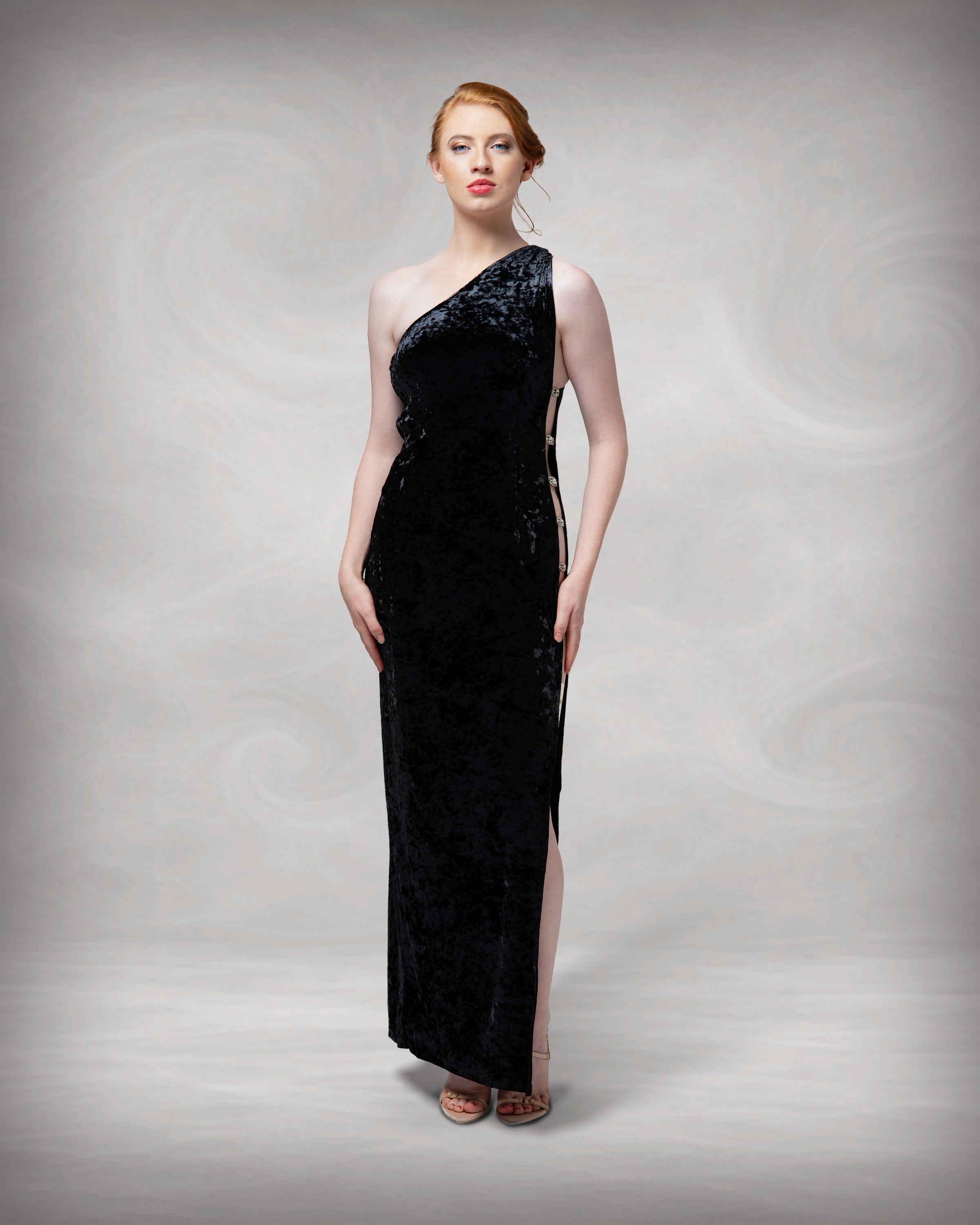 Woman wearing a black one-shoulder evening gown against a neutral background
