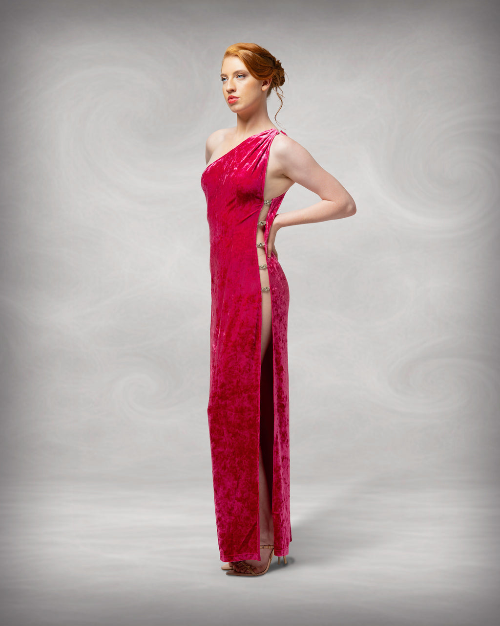 Woman wearing a red one-shoulder evening gown against a gray background [color_id:pink]